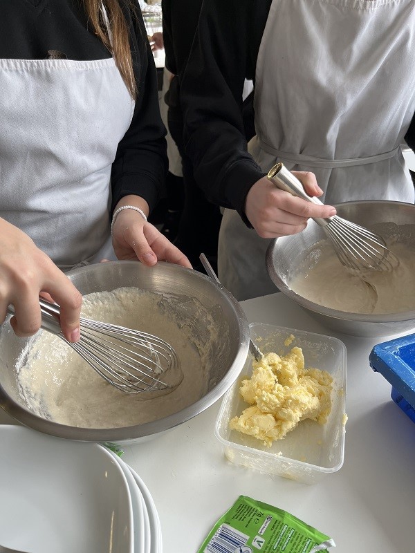 Two students whisking ingredients in pans